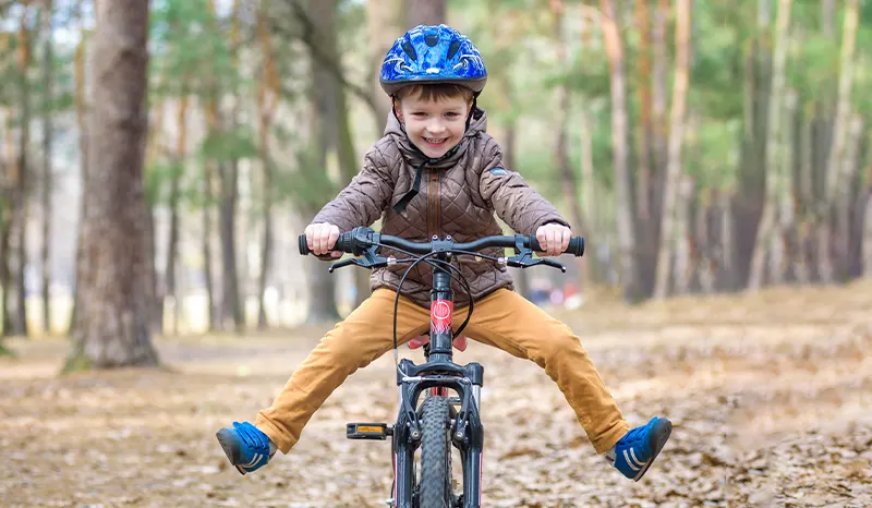 A young boy enjoying riding a bicycle in the woods.