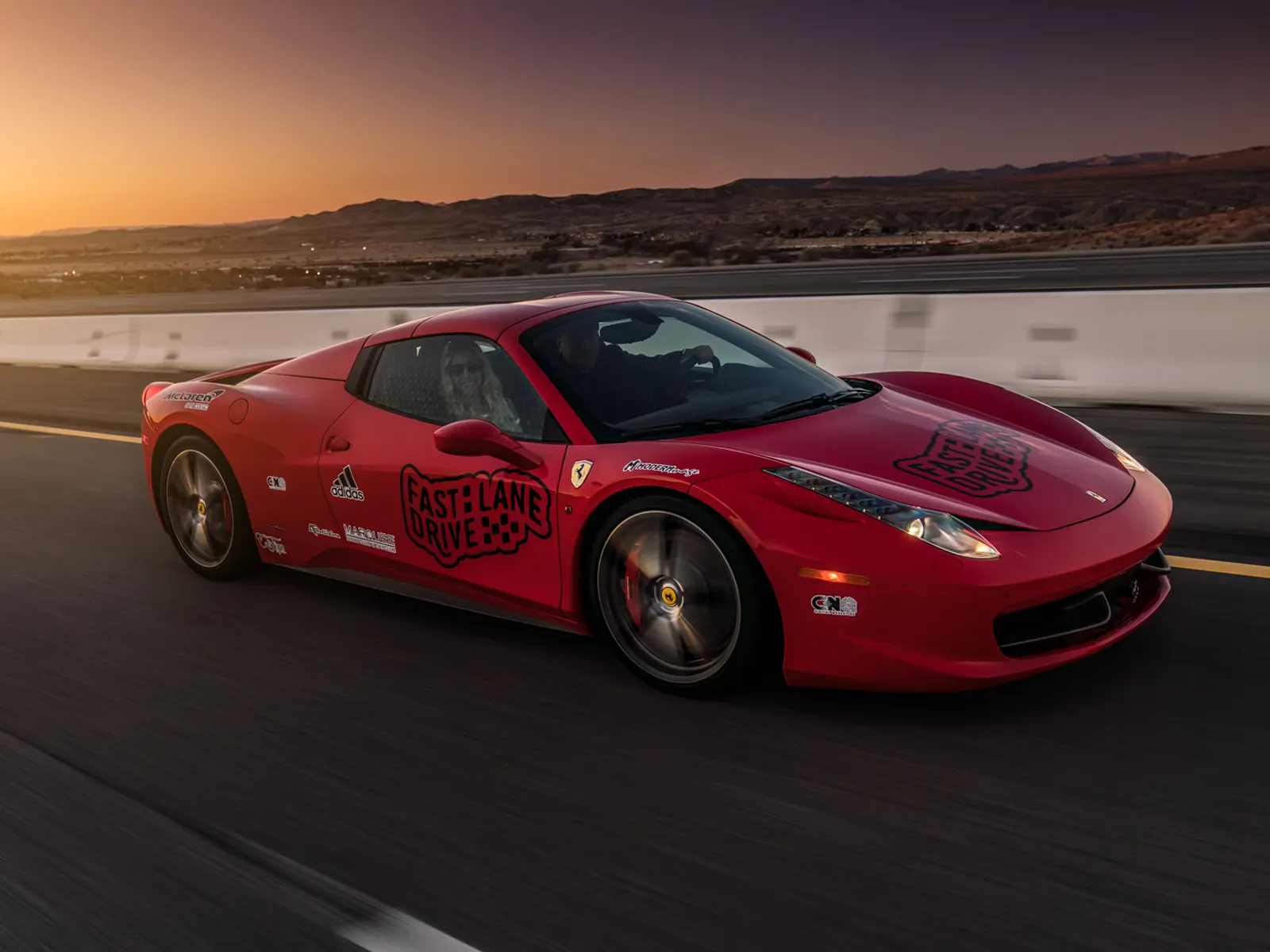 A red Ferrari with sponsorship logos driving on the freeway